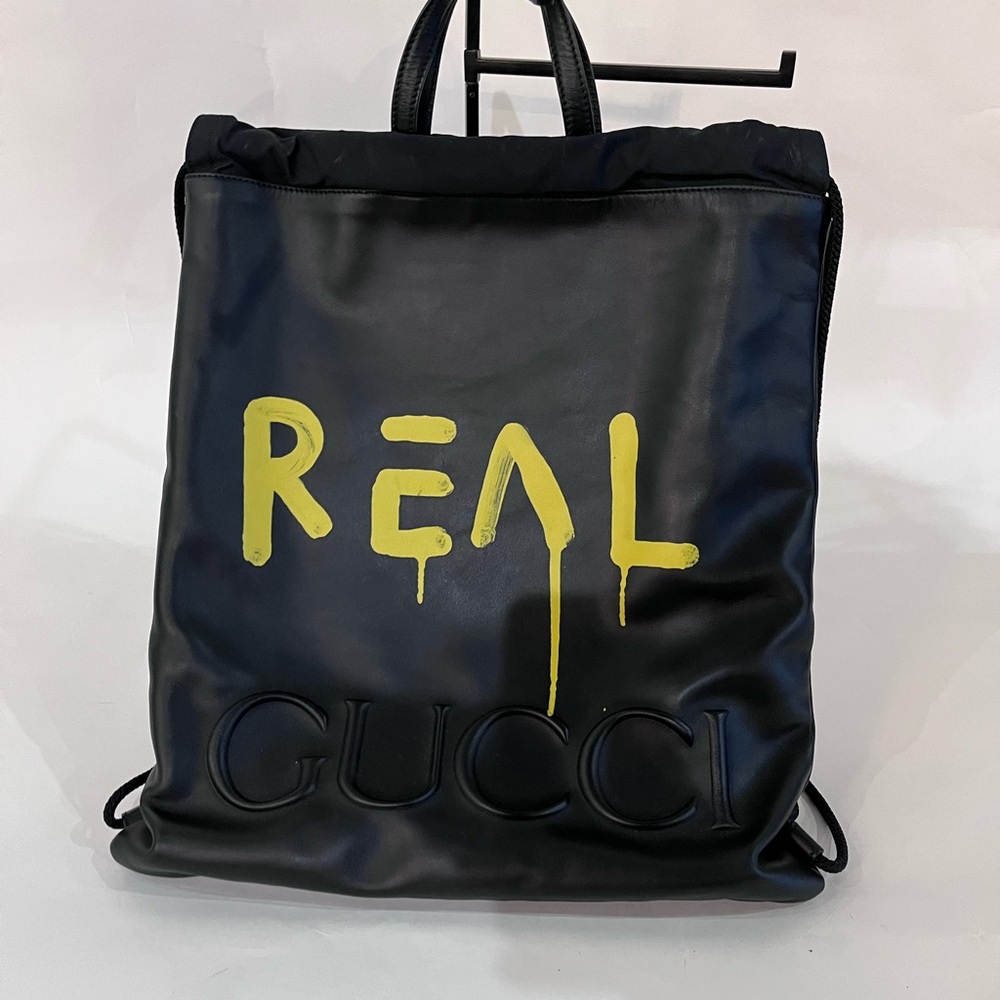 ❌ SOLD ❌ Gucci Black Leather Drawstring Backpack with Yellow 'REAL' Graphic